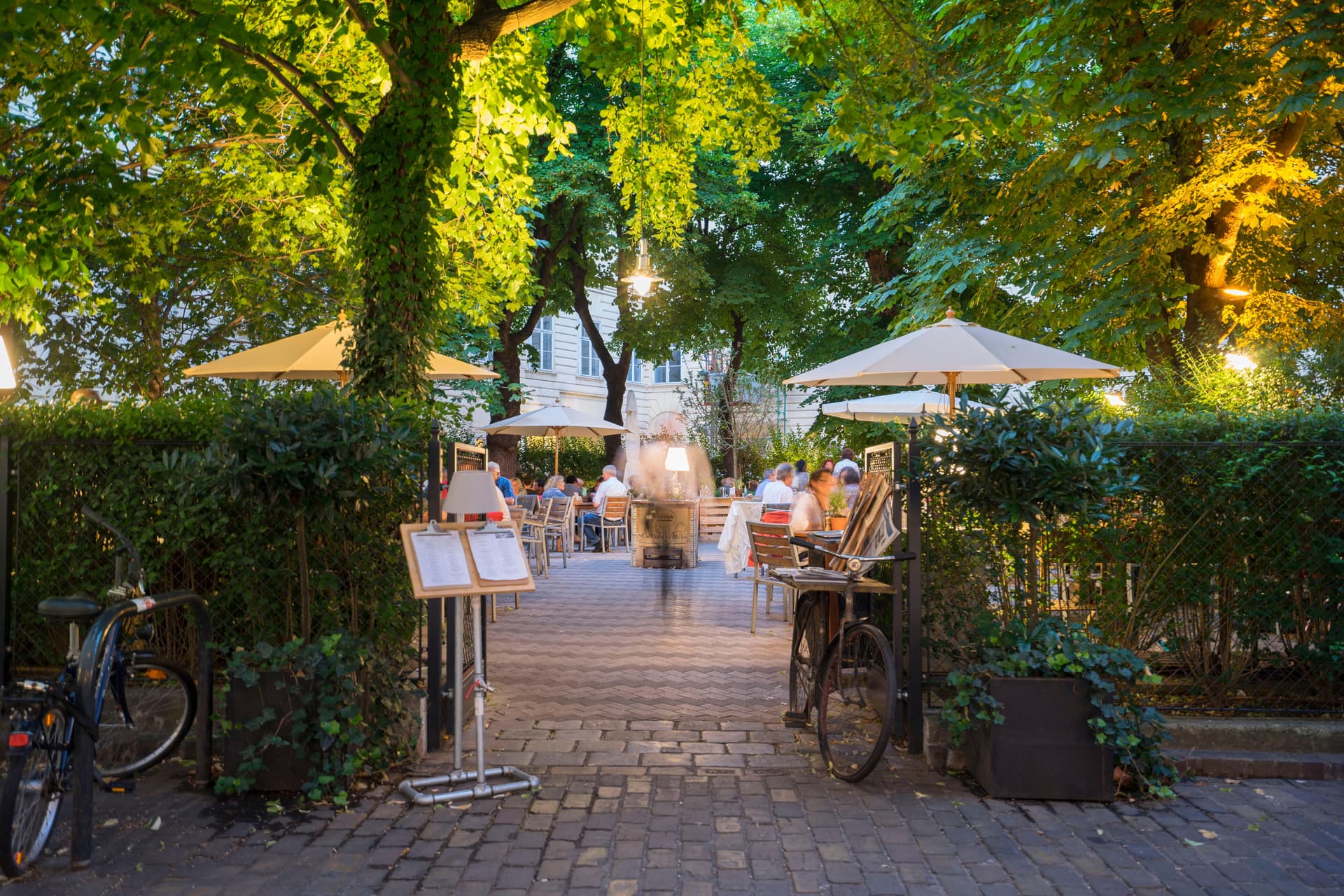 Eventlocation Wien 1010 - Versteckter Innenhof Gastgarten mit Bäumen und Sonnenschirmen für Hochzeit, Firmenfeier und Geburtstag im Café Diglas Schottenstift
